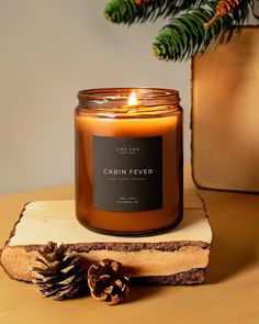 a candle sitting on top of a piece of wood next to a pine cone