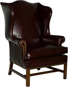 a brown leather chair with gold trimmings on the arms and back, sitting in front of a white background