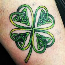 a green four leaf clover tattoo on the leg