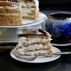 a piece of cake on a plate with a fork next to it and a cup of coffee in the background