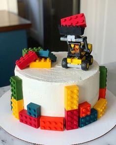 a cake decorated with lego blocks and a toy car on top, sitting on a table