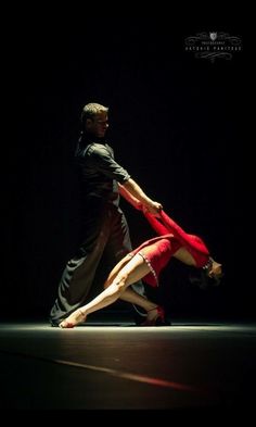 two people are dancing in the dark with their legs spread out and one person is bending over