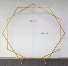 a golden frame with measurements on it in front of a white wall and grey carpet