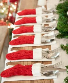 the table is set with silverware and red mittens on it, along with forks and spoons