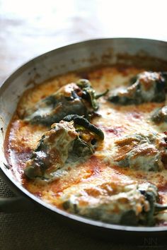 a close up of a pan of food with cheese and spinach in it on a table