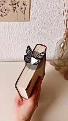 a person holding an open book with a butterfly on it