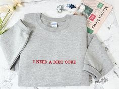 I NEED A DIET COKE Embroidered Sweatshirt | Cozy Unisex Crewneck | Funny Soda Lover Gift | Custom Color Options 🌟Showcase your love for Diet Coke with our embroidered sweatshirt, featuring the playful declaration 'I NEED A DIET COKE'. Designed for comfort, this cozy unisex crewneck is perfect for any casual occasion. Ideal for soda enthusiasts, it comes with custom color options to suit your style. A humorous, tailor-made gift for friends and family! 🌟 Premium Quality Sweatshirt 🌟 🌟Materials Diet Coke Sweatshirt, Coke Gifts, Text Embroidery, Sweatshirt Embroidery, Diet Coke, Mens Long Sleeve Tee, Embroidered Sweatshirts, Embroidery Ideas