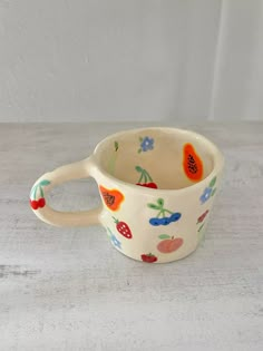 a white cup with fruit designs on it