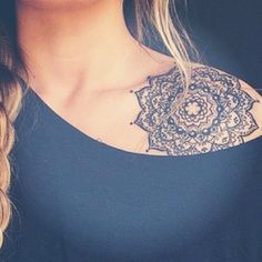 a close up of a woman wearing a black top with a flower tattoo on her chest