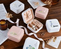 several small jewelry boxes on a table with flowers and pearls in them next to a candle