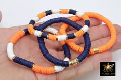 Navy Blue, Orange, White, and Gold Bracelets in Heishi Beads by Regina Harp Designs These bracelets are in a Navy Blue, Soft Orange, White, and Gold colors with your choice of bracelet style. They can be made with our other bead colors as well; message us if you would like to customize your bracelet.  If you need a smaller or extra large size in the bracelet, please leave us a note with your order. **SPECIFICATIONS** Measurements Approximately: Length is 6.5~7 inches; leave a note if you need a Navy Blue Heishi Bracelets, Blue And Orange Clay Bead Bracelet, Auburn Clay Bead Bracelet, Georgia Clay Bead Bracelet, Orange Clay Bracelets, Clay Bead Bracelet Ideas School Spirit, Navy Blue Clay Bead Bracelets, Orange And Blue Bracelet, School Spirit Clay Bead Bracelet