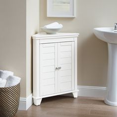 a white cabinet sitting next to a sink in a room with beige walls and wooden floors