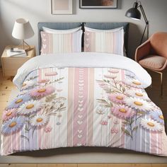 a bed with pink and white flowers on it next to a chair in a room