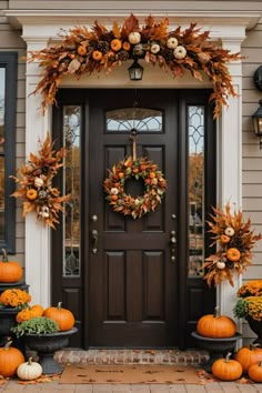 a front door decorated for fall with pumpkins and gourds