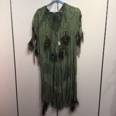 a green shirt with feathers hanging on a hanger in front of a white wall