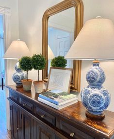 a blue and white vase sitting on top of a wooden table next to a lamp