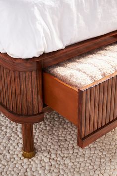 a wooden bed frame with two drawers and a white pillow on the top of it