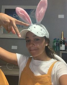 a girl wearing an easter bunny hat and pointing to the side with her hand on top of her head