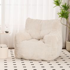 a living room with a white chair and a potted plant on the side table