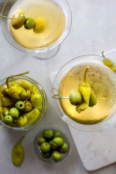 two glasses filled with white wine and green olives