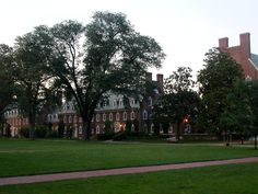 a large brick building sitting on top of a lush green field next to tall trees