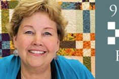 a woman smiling in front of a quilt