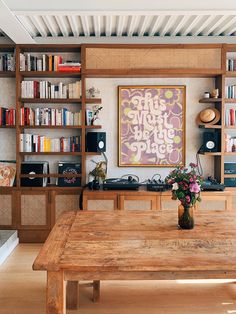 a wooden table sitting in front of a book shelf filled with books