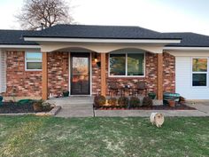 a dog is standing in front of a brick house with a patio and table on the lawn