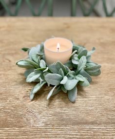 a candle is sitting on a table with greenery