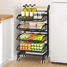 a black rack filled with fruits and vegetables next to a white refrigerator in a kitchen