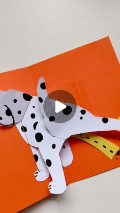 a paper cut out of a dalmatian dog on an orange background