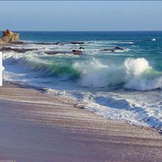 waves crashing on the beach with rocks in the background