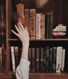 a person reaching for books on a book shelf