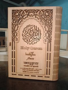 an intricately carved wooden book with arabic writing on the front and back cover, sitting on top of a table