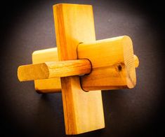 a wooden cross made out of wood on a black surface with one piece missing from it