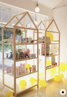 a display case with yellow balloons in the shape of a house and some bookshelves