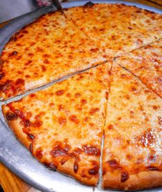 a cheese pizza cut into four slices on a metal platter with one slice missing