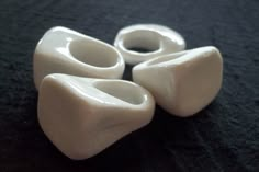 four white vases sitting on top of a black cloth covered tablecloth in the shape of hearts