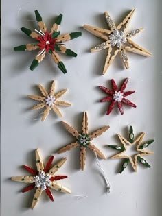 six wooden snowflakes are arranged on a white surface, each decorated with different colors and sizes