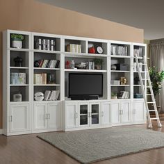 a living room with white bookcases and a ladder to the top of it