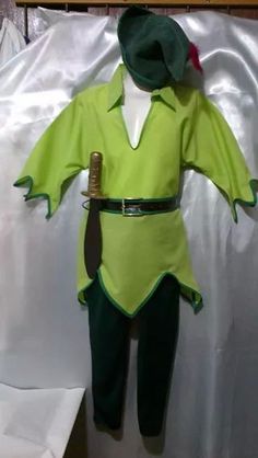 a green and white costume is hanging on a wall next to a sheet of paper