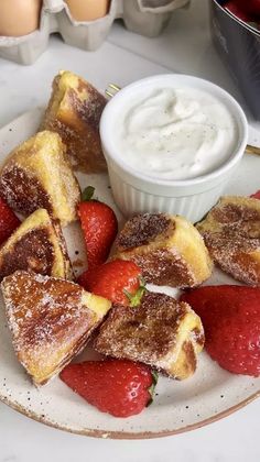 strawberries and french toast on a plate next to an egg yogurt container