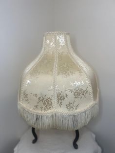 a white lamp shade with fringe trim on it