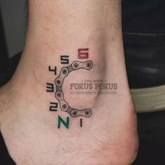 a close up of a person's foot with a bike chain tattoo on it