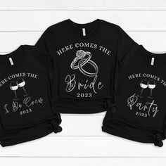 three black shirts with the words here comes the bride and groom printed on them, sitting next to each other