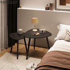 a small table with a lamp on it next to a bed