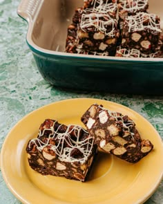 some brownies on a yellow plate with white sprinkles next to it