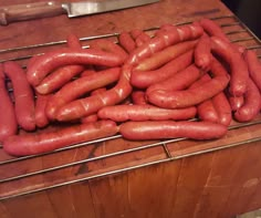 a bunch of hot dogs sitting on top of a wooden table next to a knife