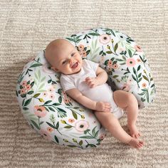 a baby laying on top of a flowery pillow in the middle of a room