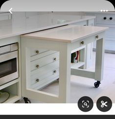 a kitchen with white cabinets and an island on wheels in front of the stove top